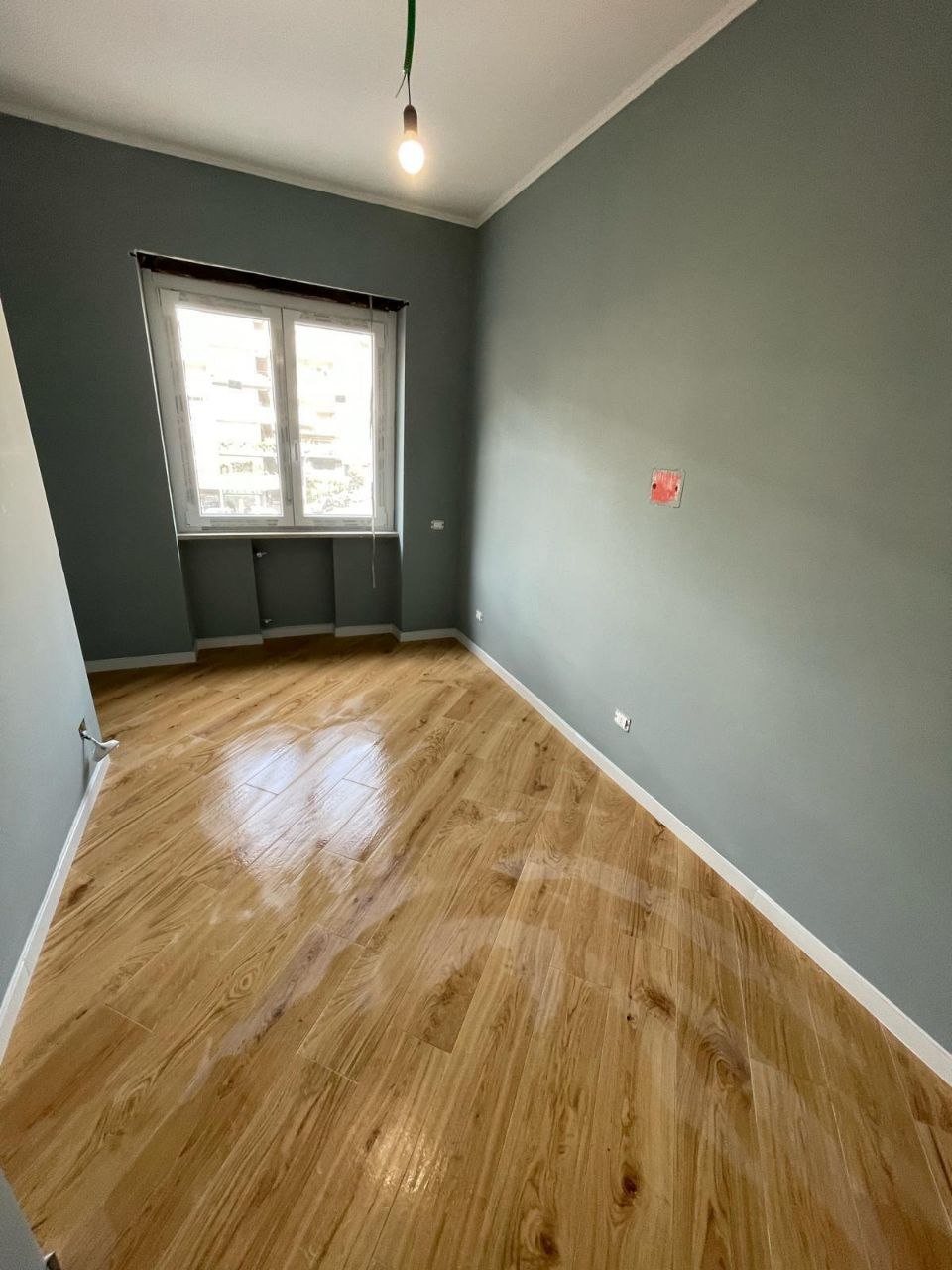 Camera ristrutturata con pavimento effetto legno e pareti tinteggiate