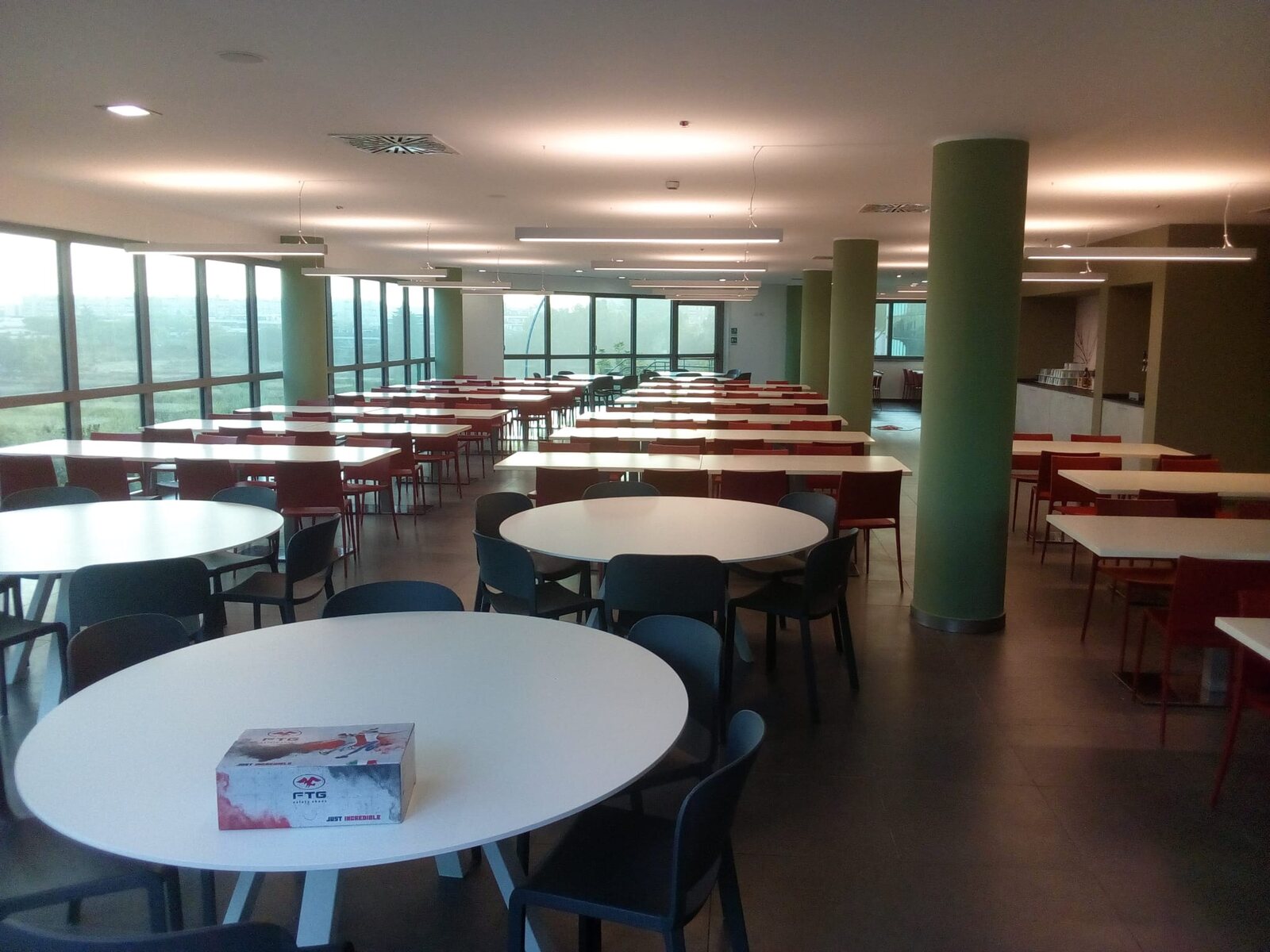 Sala ampia rinnovata con tavoli e pilastri verdi