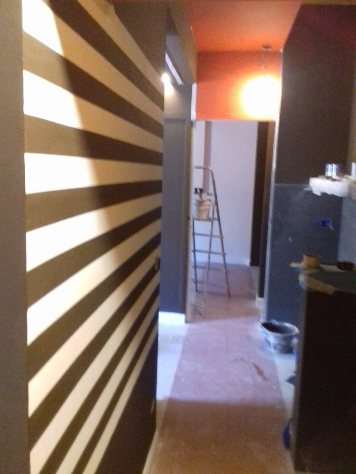 Interno con parete a righe e accesso a stanza in lavorazione